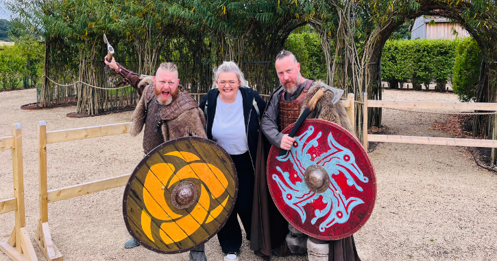 woman standing and smiling with two men dressed as Vikings at Kynren, Bishop Auckland.